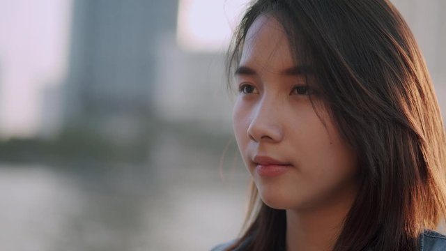 Teenager Asian woman show feelings lonely, desolate, alone at sunset. Close up of asia girl on face expression 