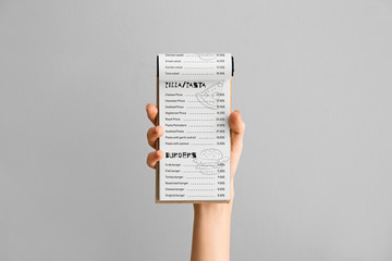 Female hand with menu on grey background - obrazy, fototapety, plakaty