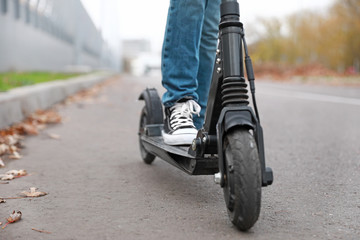 Teenage boy riding kick scooter outdoors, closeup © Pixel-Shot