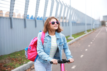 Obraz premium Teenage girl riding kick scooter outdoors