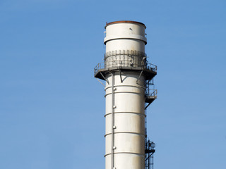 a tall industrial smoke stack on a blue sky