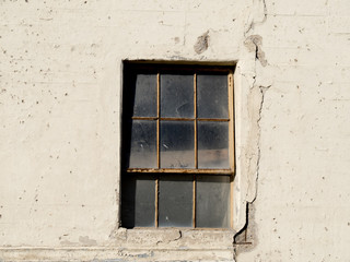 an old factory window with cracks in the concrete wall around it
