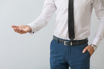 Young businessman holding something on grey background