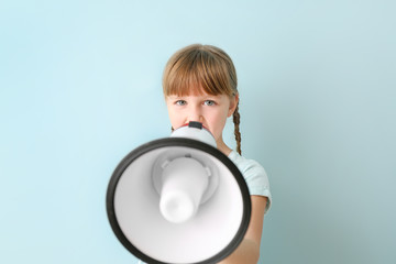 Cute little girl with megaphone on color background