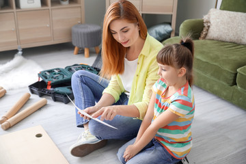 Mother and her little daughter assembling furniture at home