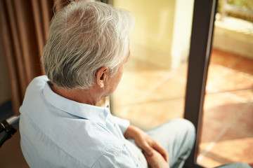 lonely asian elderly man sitting in wheel chair in nursing home