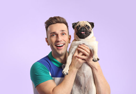 Handsome man with cute pug dog on color background