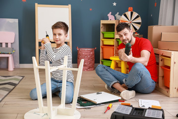 Father and his little son assembling furniture at home