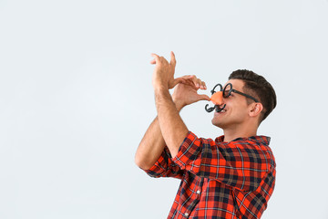 Man in funny disguise on light background. April fools' day celebration