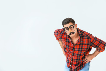 Man in funny disguise on light background. April fools' day celebration