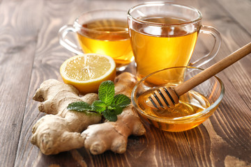 Cups of healthy drink with lemon, ginger and honey on wooden table