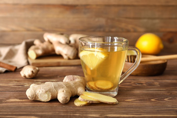 Cup of healthy drink with lemon and ginger on wooden table