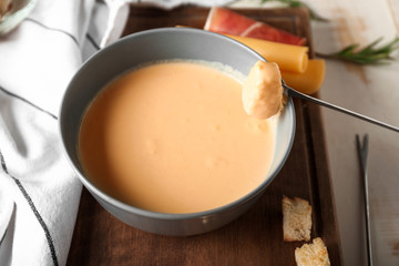 Dipping of crouton into cheese fondue, closeup