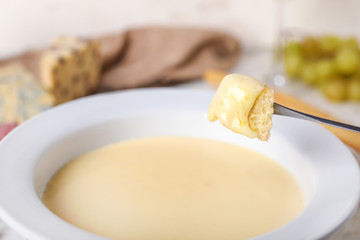 Dipping of crouton into cheese fondue, closeup