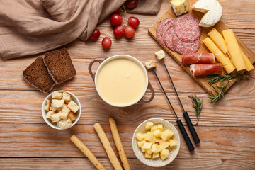 Fototapeta premium Cheese fondue with snacks on wooden background