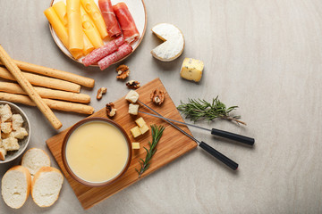 Cheese fondue with snacks on grey background
