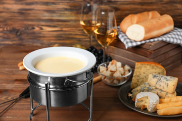 Cheese fondue with snacks on wooden background
