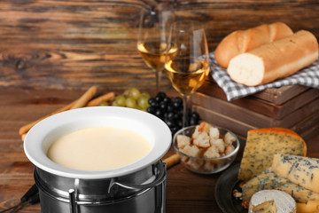 Cheese fondue with snacks on wooden background