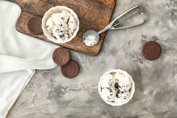 Bowls with tasty ice cream and cookies on grey background