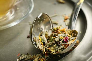 Dry tea leaves and infuser on table, closeup