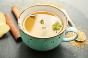Cup of hot tea with cinnamon and ginger on table