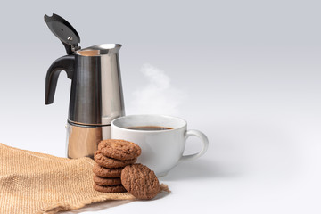 cookies on sack cloth with cup of coffee and coffee pot on whitebackground