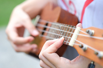 Obraz premium A young woman playing string music ukulele in the summer