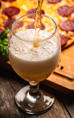 Freshly brewed beer and pepperoni pizza in bar. Selective focus. Shallow depth of field.