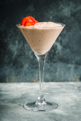 Chocolate yogurt with chia seeds and strawberry in martini glass on the rustic wooden background. Selective focus.