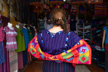 Una mujer  se prueba ropa tipica de Santa Catarina Palopo y muestra la parte trasera.