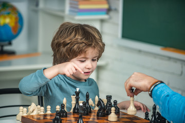 Kids educational games, early development. Boy kid playing chess at home. Games and activities for children. Family concept.