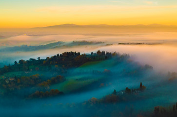 Tuscany hilly, foggy, sunset scenery; as seen from one of the towers in San Gimignano, Italy. - obrazy, fototapety, plakaty