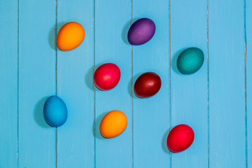 colored Easter eggs on light blue wooden boards top view. red, blue, orange, purple, green. festive background.