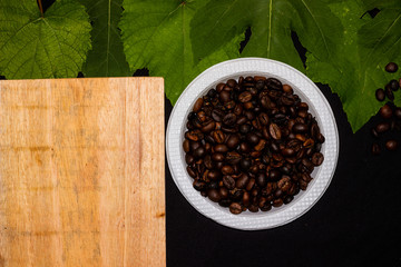 Border Coffee beans with green leaves isolated against a black background. captured from top view