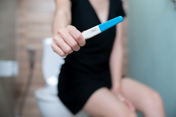 Female hand holding negative pregnancy test, with not pregnant results.