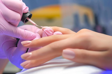 De meester van de manicure behandelt de schellak van de cliëntspijkers, handenclose-up. Professionele manicure in schoonheidssalon. Hygiëne en verzorging van de handen. Schoonheidsindustrie concept.