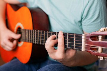 Fototapeta na wymiar guy plays acoustic guitar, man finger holding a bar chord. learn to play a musical instrument