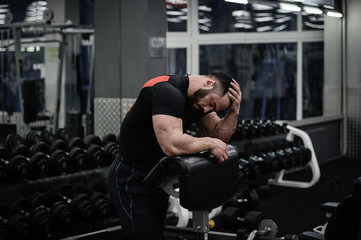 steroid doping problem and trouble headache tired sport man hold his head with hand in fitness gym after heavy failure loss workout
