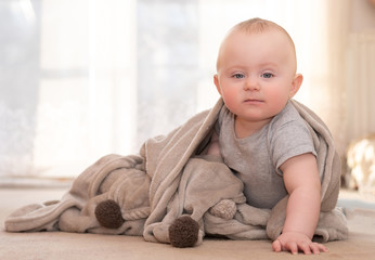 Naklejka premium Caucasian infant sitting on floor leaning on one hand