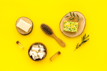 Cosmetics for hair care with argan and jojoba oil on yellow background top-down