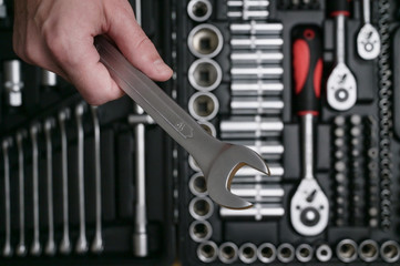 human hand holding chrome stainless car auto socket wrench on toolbox background for maintenanace in workshop