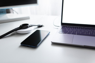 laptop with phone computer mouse and smart watch charging on wireless charger