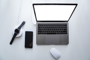laptop with phone computer mouse and smart watch charging on wireless charger