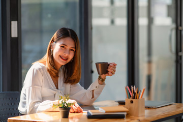 businesswoman having tea or coffee in home office	