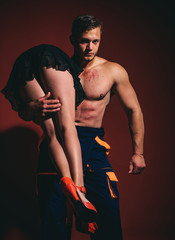 Firefighter sexy body muscle man holding saved sexy woman. Intimate relationship and sexual...