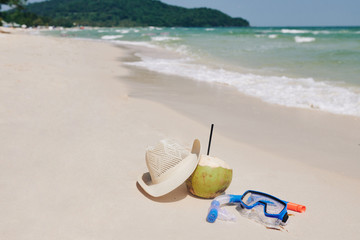 Snorkeling mask, straw hat and coconut cocktail on sandy beach, summer activities concept