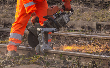 ein Arbeiter der Bahn zerschneidet mit einem Trennschleifer  Bahnschienen