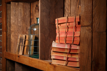 Old books, rewound with a rope, stand on a wooden shelf. 