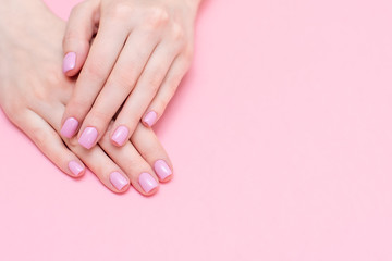Female hands manicure close up view on pink knitted sweater background. Nail painting effects. Manicure salon banner concept