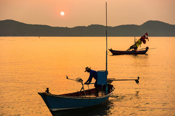 Chanthaburi, Thailand - February, 02,  2020 :Beautiful sunrise over sea with Silhouette of fishermen with yellow and orange sun in the background.